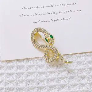 Close-up of golden snake brooch with sparkling crystals and green gem eyes on fabric