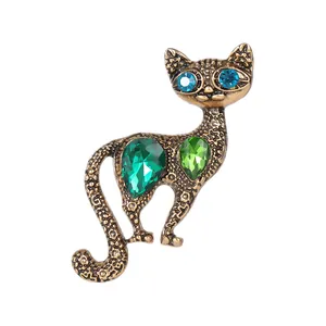 Vintage cat brooch with green crystals and blue rhinestone eyes on antique gold metal