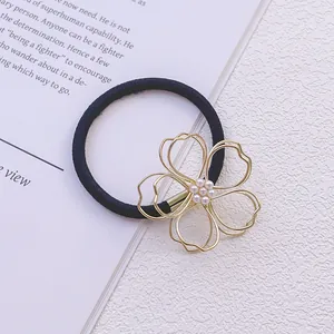 Vue détaillée d'un élastique à cheveux noir avec un charm fleur en perles dorées