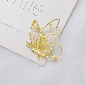 Gros plan détaillé d'une broche papillon évidée dorée avec détails en cœur sur soie