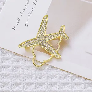 Broche avion et cœur dorée avec strass scintillants sur un tissu blanc texturé