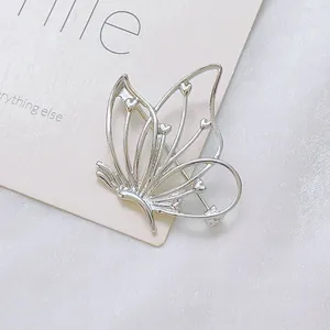Détail d'une broche papillon argentée avec ailes évidées et motifs de cœurs
