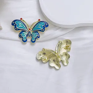 Exquisito broche de mariposa con esmalte verde y baño de oro sobre tela blanca