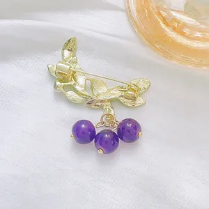 Elegant gold leaf blueberry brooch with purple beads on white silk background