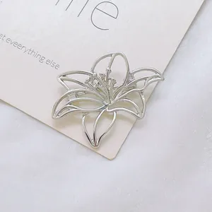 Gros plan détaillé d'une broche fleur de lys argentée montrant les détails ajourés