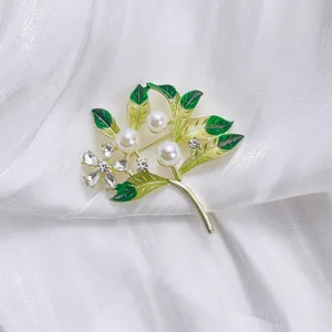 Vintage green enamel flower brooch with pearls and cubic zirconia on white satin