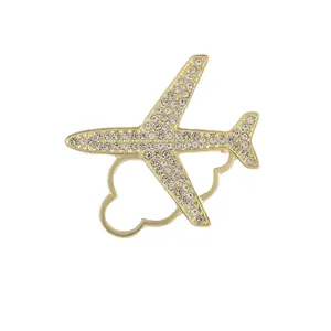 Broche avion minimaliste dorée ornée de strass brillants sur un fond blanc pur