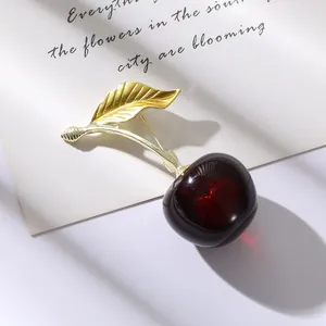 Broche cerise élégante avec feuilles dorées et fruits rouges aux reflets de cœur
