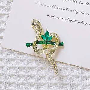 Detailed close-up of a vintage gold snake brooch with green gems and white crystals