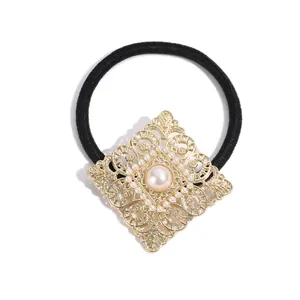 Élastique à cheveux avec breloque en filigrane doré et perles sur fond blanc pur