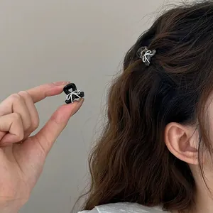 Mini hair claw clip with white bow design shown in hand and worn on model hair
