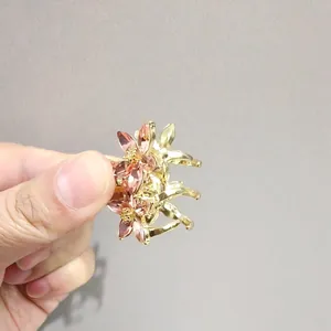 Détail d'une petite pince à cheveux fleur dorée avec pétales en cristal rose et perles