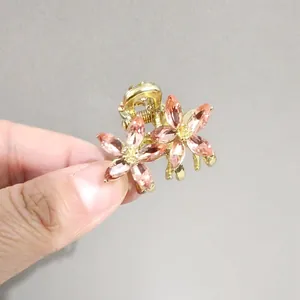 Détail d'une mini pince à cheveux dorée avec cristaux roses montrant sa petite taille