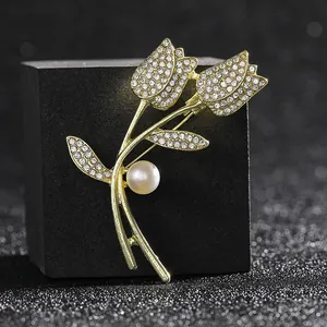 Close-up of golden tulip brooch with sparkling rhinestones and a white pearl accent