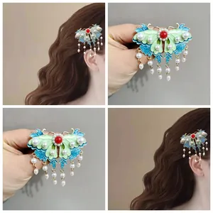Detalle de pinza de mariposa con esmalte azul, perlas y borlas colgantes