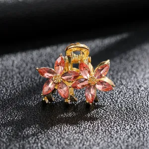 Mini pince à cheveux dorée avec fleurs en cristal et strass champagne sur fond noir