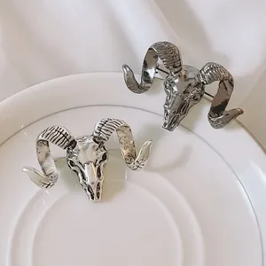 Vintage ram head skull brooches in silver and charcoal finish on a ceramic plate