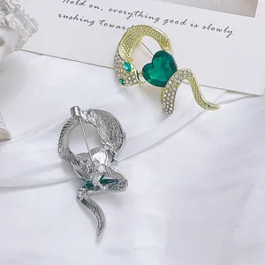 Broche serpent élégante avec cristal émeraude en finitions dorée et argentée