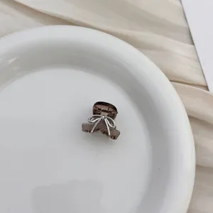 Detailed view of a mini translucent coffee hair claw clip with silver bow design