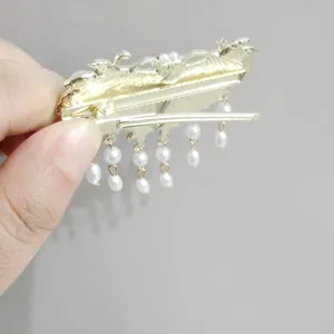 Detalle de horquilla dorada vintage con perlas blancas y flecos largos de borla