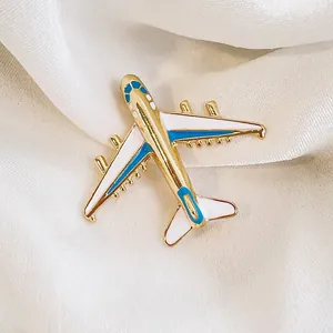 Élégante broche avion dorée avec détails en émail bleu et blanc pour femmes