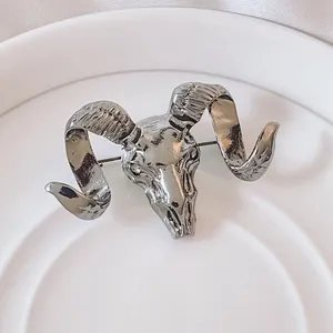 Close-up of vintage silver ram skull brooch with textured spiral horns and detailed finish