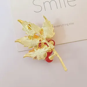 Elegant maple leaf brooch with red berries and golden finish shown from back view