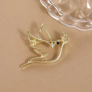 Macro detail of golden dove brooch with olive branch and sparkling black rhinestone eye