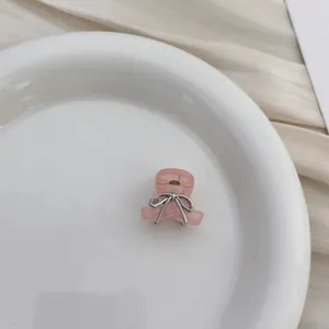 Close-up of a pink bow hair claw clip decorated with rhinestones on a white plate