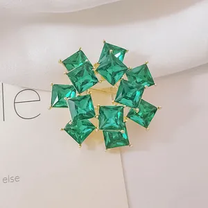 Detalle macro de un broche de flor con cristal verde y baño de oro con piedras talladas