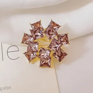 Elegante broche de oro con cristallen morados cuadrados y circonitas en tela blanca