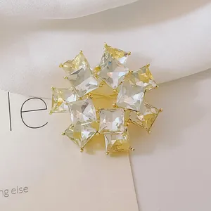 Detalle de elegante broche floral radial con cristales cuadrados de champán y dorado