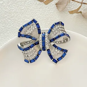 Elegante broche de lazo plateado con diamantes de imitación azul oscuro y cristales