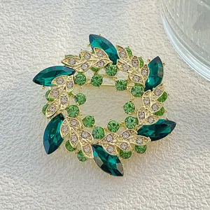 Elegante broche de corona dorada con cristales verdes y diseño de hojas brillantes