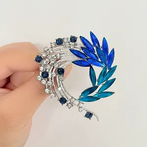 Elegante broche cola de fénix plateado con cristales azules en diseño circular