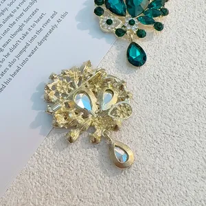 Broche vintage dorée avec cristaux goutte vert émeraude et vue de l'épingle de sûreté