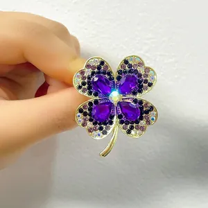 Elegant four-petal flower brooch with purple crystals and gold plating on white background