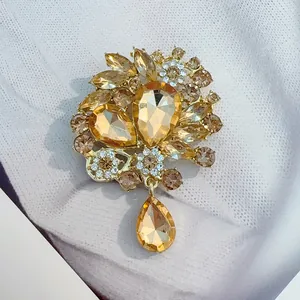 Détail de la broche fleur en cristal champagne doré avec pendentif goutte élégant