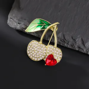 Macro shot of cherry brooch with rhinestones and red heart gem on textured stone