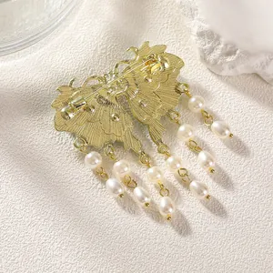 Elegant butterfly brooch with pearl tassels and golden metal base shown from a side view