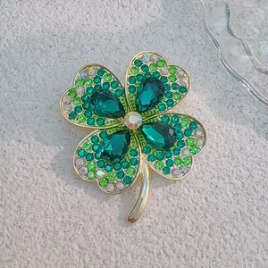 Detail view of crystal four-leaf flower brooch with green stones and gold metal base