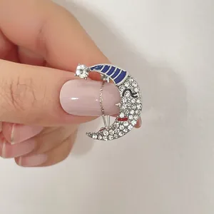 Handheld silver crescent moon brooch with sparkling rhinestones and blue enamel details