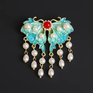 Vintage butterfly brooch with blue enamel wings, pearls, and dangling tassels on black