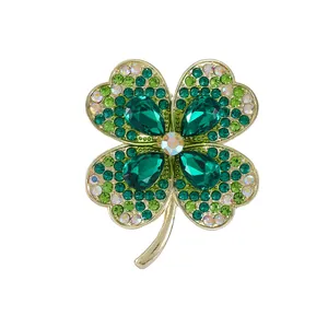 Elegant gold four-leaf flower brooch with deep green crystals and sparkling rhinestones