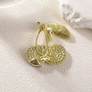Golden cherry brooch with detailed safety pin clasp and textured metal finish on back