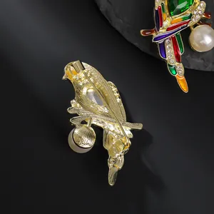Elegant parrot brooch with colorful enamel, crystals and large pearl detail in gold finish