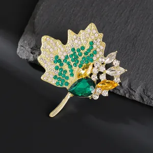 Détail d'une broche feuille d'érable avec strass verts et une grande gemme émeraude