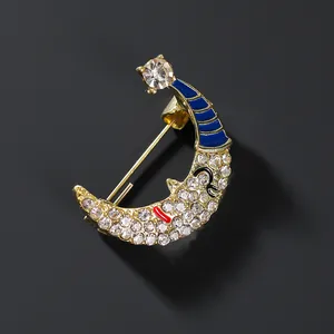 Detailed close-up of a smiling crescent moon brooch with white crystals and gold base
