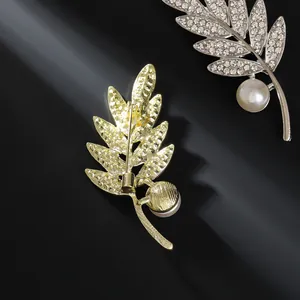 Broche élégante en forme de feuille avec strass blancs et perle blanche sur fond noir