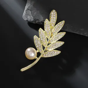Détail de la broche feuille dorée avec des strass étincelants et une perle nacrée